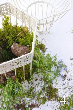 two white chairs sitting on top of a pile of dirt and grass next to each other