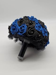 a bridal bouquet with black and blue roses on it, sitting on a white surface