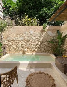 an outdoor hot tub in the middle of a patio with two chairs and a rug