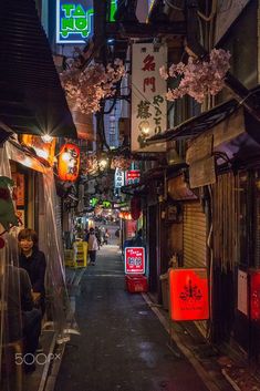 an alley way with people walking down it at night in the middle of the city