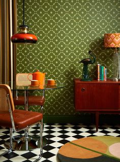 a room with a checkered floor, green wallpaper and a table with two chairs