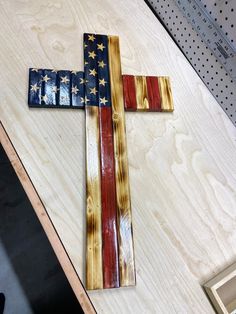 a wooden cross with an american flag painted on it sitting on top of a table