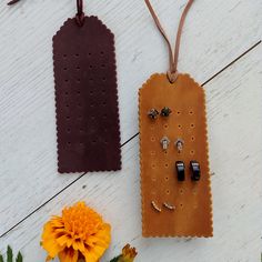 two pieces of leather hanging from strings next to flowers