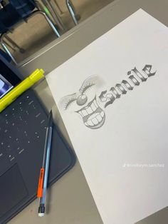 the word smile is drawn on paper next to a laptop