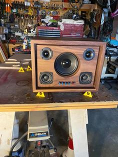 a wooden speaker sitting on top of a table in a room filled with other items