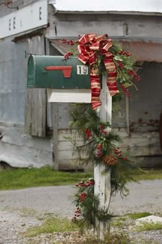 a mailbox decorated with christmas wreaths and pine cones is tied to the post