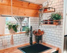 a kitchen with white tiles and wooden shelves on the wall next to a black sink