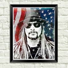 a man wearing sunglasses and a hat in front of an american flag wall hanging on a brick