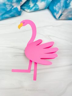 a pink paper flamingo sitting on top of a bed