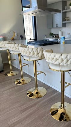 a kitchen with white counter tops and gold stools