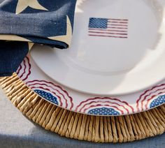 an american flag plate on top of a wicker place mat with a blue and white napkin