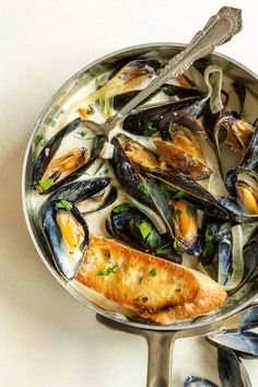 a pan filled with mussels and sauce on top of a white countertop