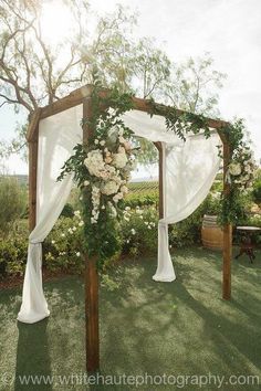 an outdoor wedding setup with white drapes and flowers