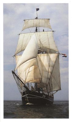 a large white sail boat sailing in the ocean