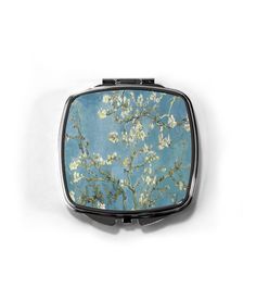 a compact mirror with an almond blossoming tree in bloom against a blue sky background