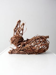 a bird made out of twigs sitting on top of a white table next to a wall