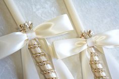 two wedding garters with white ribbons and bows on the front, one in gold