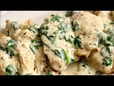 a white plate topped with ravioli covered in cheese and spinach sauce next to a fork