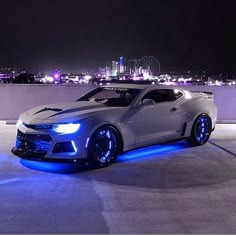 a white car with blue lights on it's side in front of a cityscape