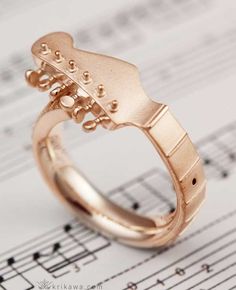 a gold guitar ring sitting on top of sheet music