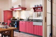 a kitchen with pink cabinets and black counter tops is seen from the doorway to the dining room