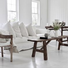 a living room filled with white furniture and pillows on top of it's couches