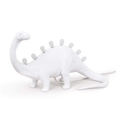 a white dinosaur lamp is shown on a white background with the cord plugged in