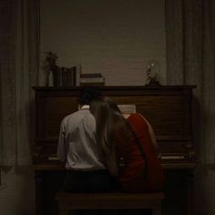 two people sitting at a piano in the dark