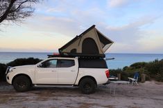 a pick up truck with a tent attached to the back in front of an ocean view