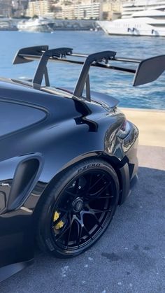 a black sports car parked next to the water