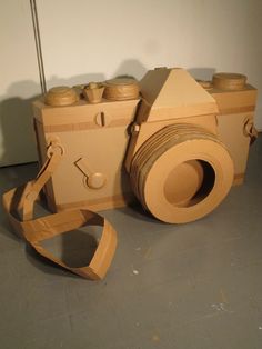 an old camera made out of cardboard with a strap around the body and two jars on top