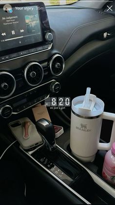 the interior of a car with various items in it, including coffee mugs and an mp3 player