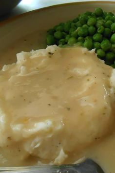 mashed potatoes, peas and gravy on a plate with a fork in it