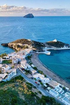 an aerial view of the beach and ocean with houses on it's shore, in front of a small island