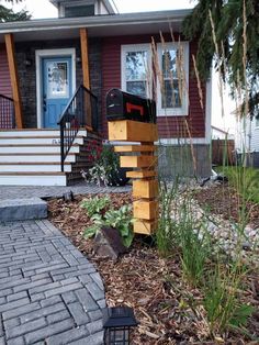 a mailbox sitting on top of a wooden post in front of a brick walkway