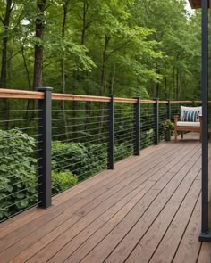 a wooden deck with metal railings and bench on it's side, surrounded by trees