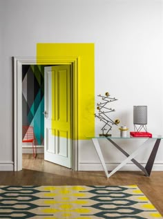 a room with white walls, yellow door and colorful rug on the wooden flooring