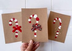 someone is holding up some cards made to look like christmas wreaths and bows on brown paper