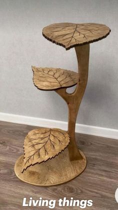 a three tiered wooden table with leaves on it