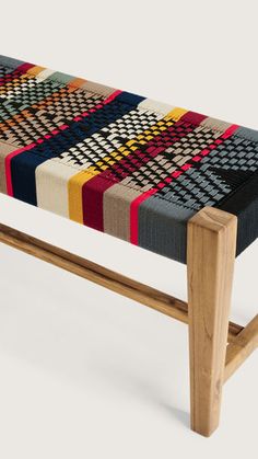 a wooden bench with multicolored plaid upholstered seat