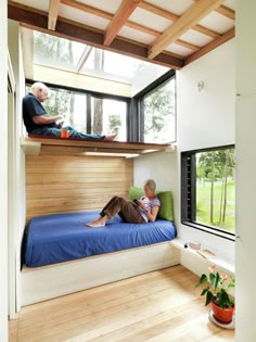 two people sitting on bunk beds in a room with wood flooring and wooden walls