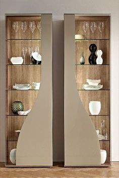 two glass shelves with wine glasses and plates on them in front of a wall mounted cabinet