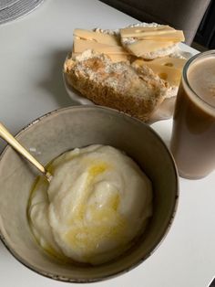 a bowl of ice cream next to two glasses of milk and bread on a table