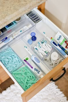 an open drawer with various crafting supplies in it on a white rug next to a counter