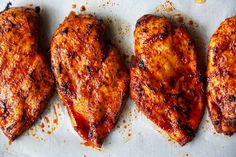 three pieces of chicken sitting on top of a piece of parchment paper covered in sauce