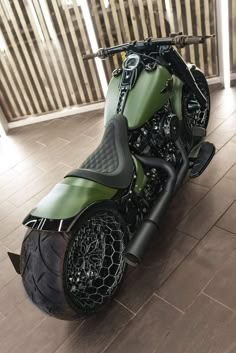 a green motorcycle parked on top of a wooden floor