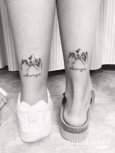 black and white photo of two legs with small tattoos on their ankles, one is holding the other's leg