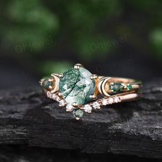 a ring with green and white stones on it sitting on top of a piece of wood