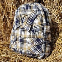 a plaid backpack sitting on top of dry grass