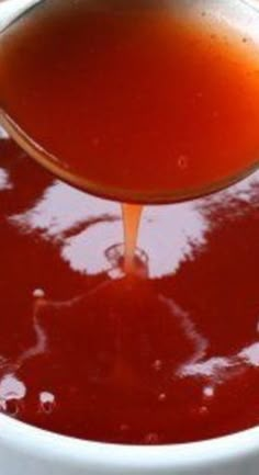 a spoon pouring sauce into a white bowl